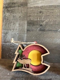 Rustic wooden Colorado ornament featuring carved animals like wolf, elk, bear, moose, bighorn sheep, and buffalo.