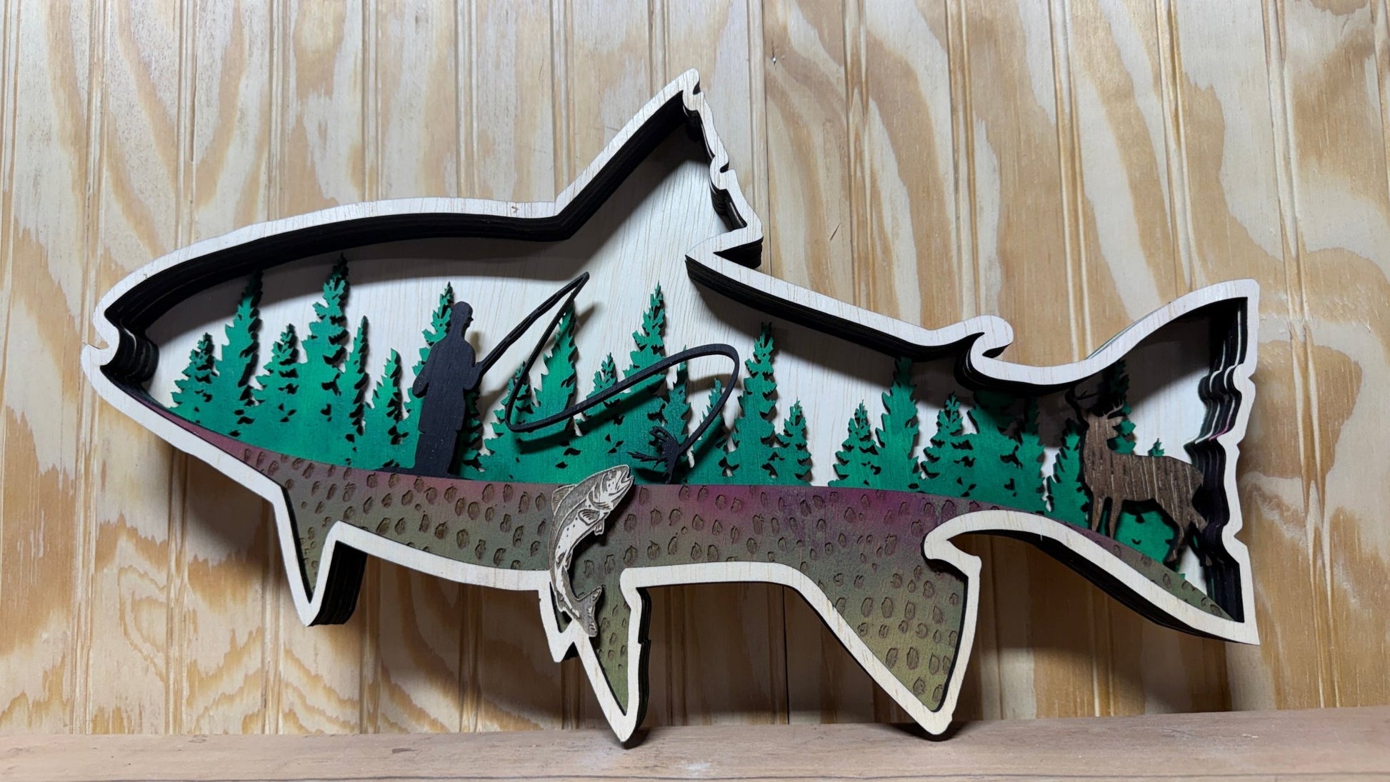 Handcrafted wooden trout wall art by Bunkhouse Studio, featuring a fly fisherman scene for rustic cabin or lodge decor.