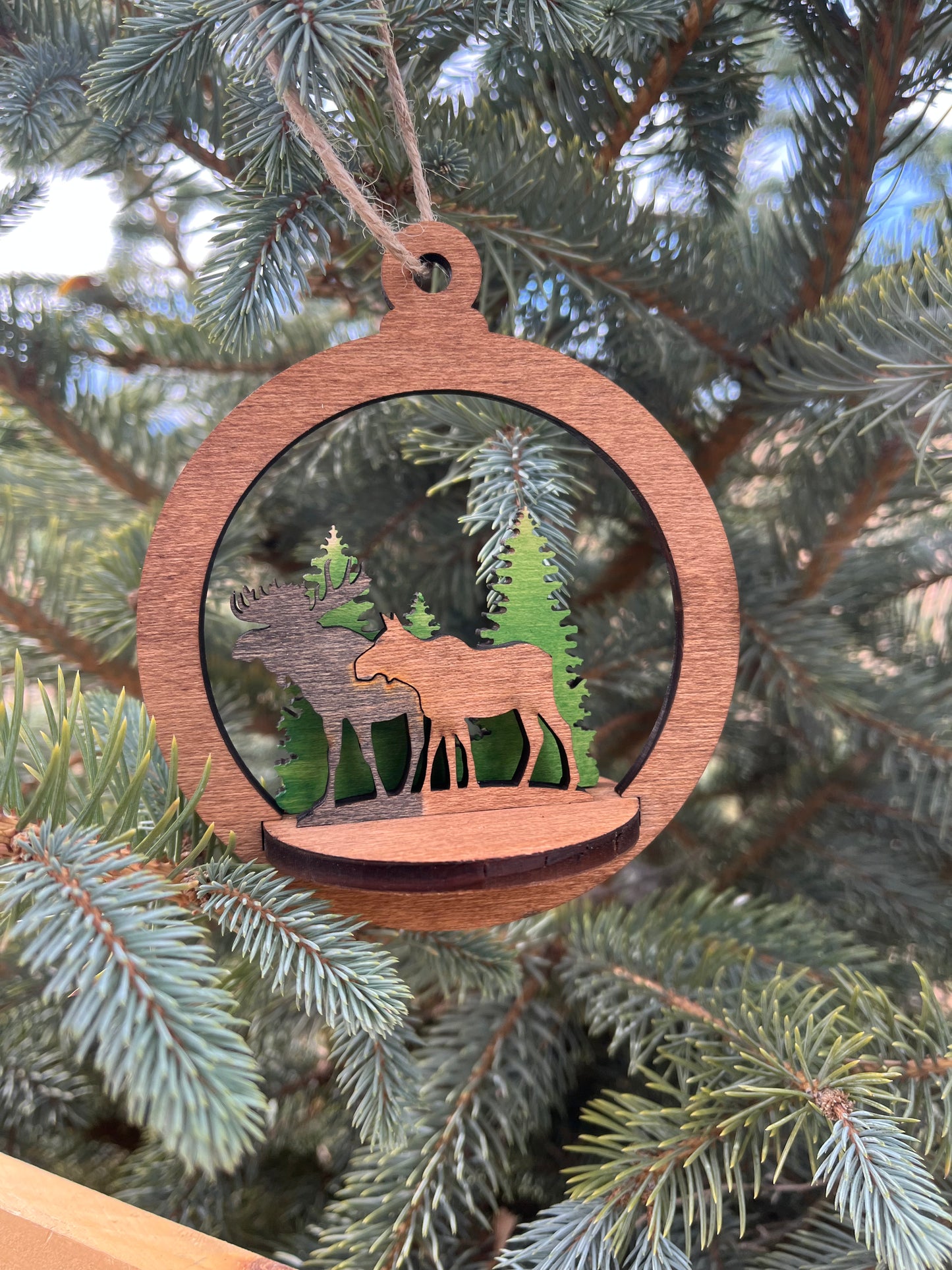 Two-layer circular ornament by Bunkhouse Studio LLC with intricate design, hanging on a rustic string against a neutral background.
