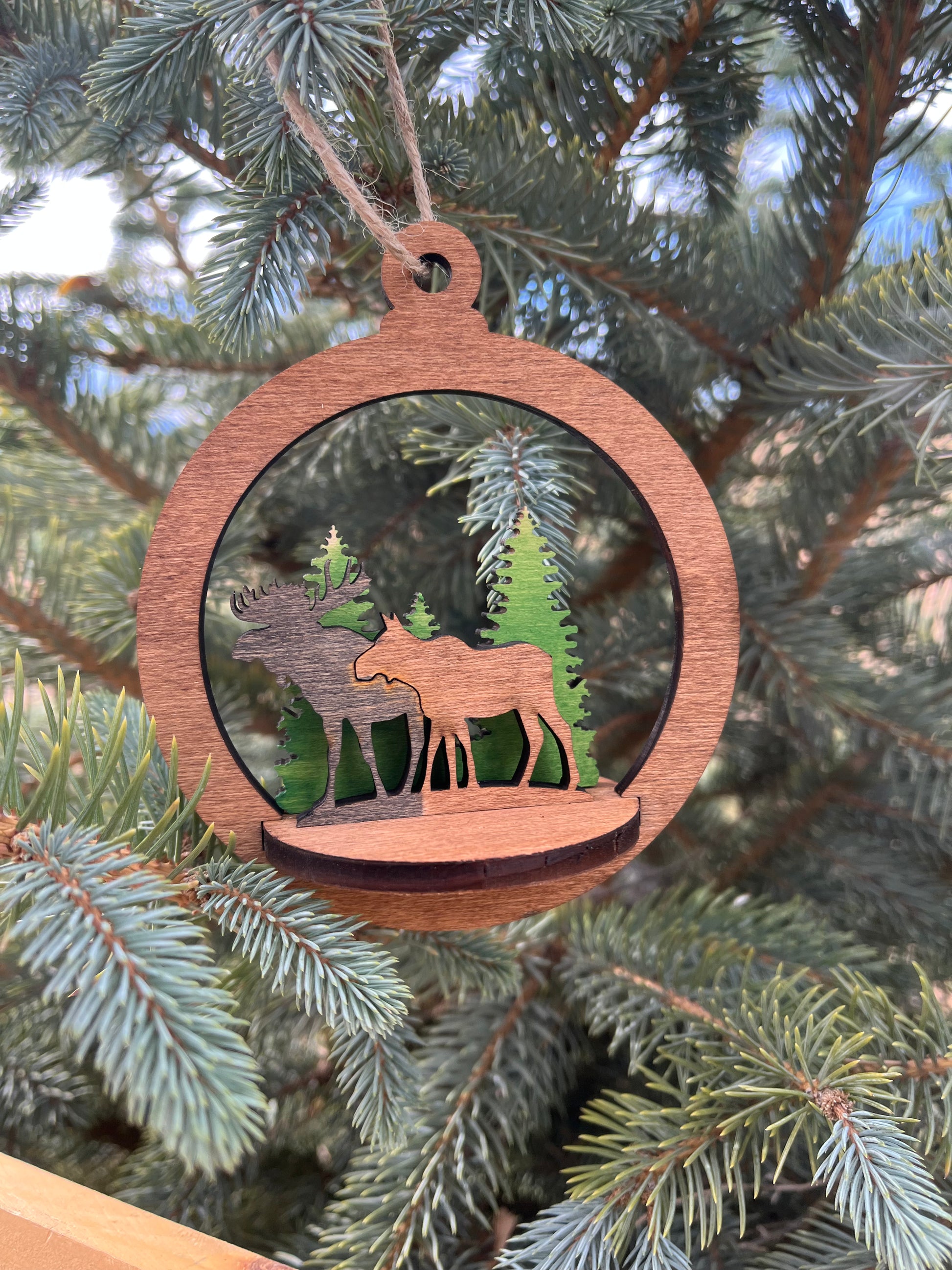 Two-layer circular ornament by Bunkhouse Studio LLC with intricate design, hanging on a rustic string against a neutral background.